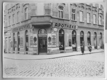 Historische Aufnahme: die Linden-Apotheke an der Straßenecke, Schriftzug „Linden-Apotheke“ über den Schaufenstern, Kopfsteinpflaster
